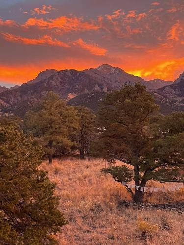 a sunset over a field with trees and mountains at White Lotus House in Crestone