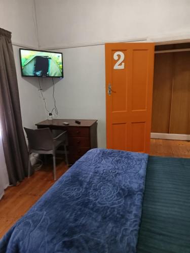 a bedroom with a bed and a desk and a television at PMB Backpackers Lodge in Pietermaritzburg