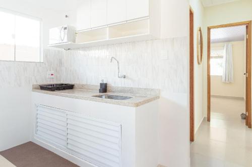 a white kitchen with a sink and a counter at Bela casa de praia sossegada no Centro de Búzios in Búzios