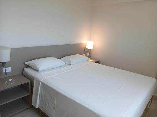 a large white bed in a room with a lamp at Salinas Park Resort in Salinópolis