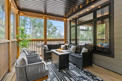 a screened in porch with couches and a table at Luxe Forest Retreat HotTub, Sauna, PoolTable, View in Dwight