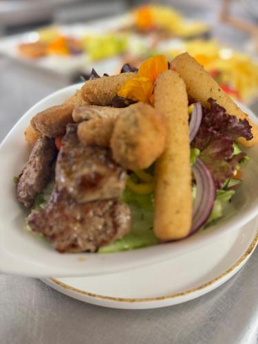 a plate of food with a salad and french fries at Gasthof Neumeister in Stumm