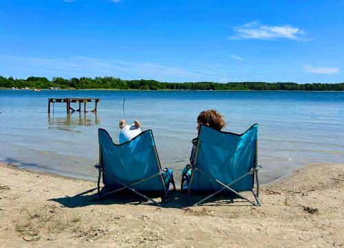 two people sitting in chairs on the beach at Mazury w Zasięgu in Brajniki