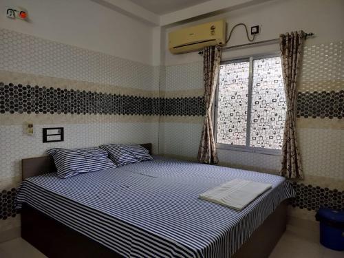 a bedroom with a bed with blue and white stripes at Swarnamayee Resort in Purbbadulki