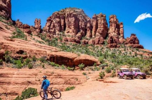 a man riding a bike in the desert with a jeep at Sedona Retreat with Hot Tub and Views for Family in Sedona