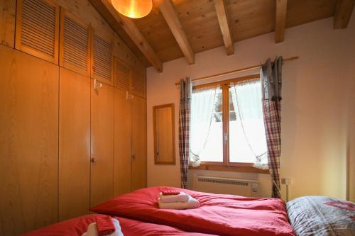 a bedroom with a red bed and a window at Tolle 2,5 Zimmer Galeriewohnung in Grindelwald