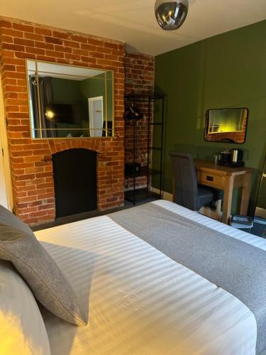 a bedroom with a bed and a brick fireplace at Oaklands Hotel in Norwich