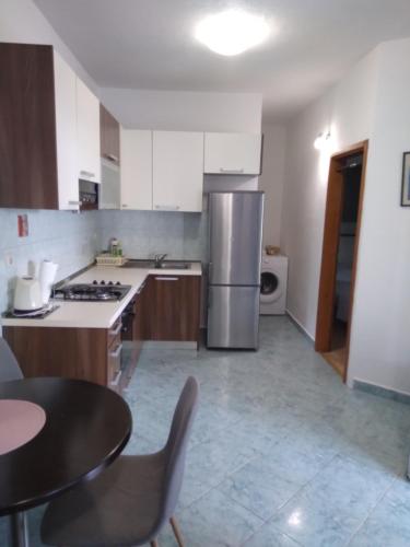 a kitchen with a stainless steel refrigerator and a table at Apartment Hortenzija in Baška Voda