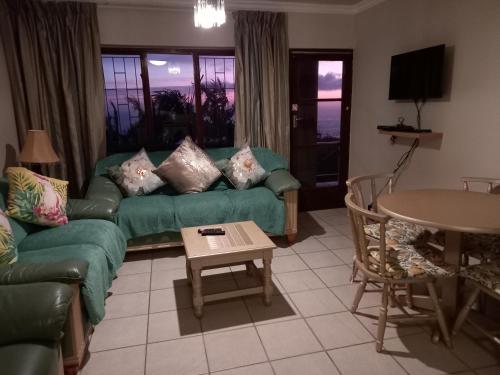 a living room with a green couch and a table at 110 Bay View in Brenton-on-Sea