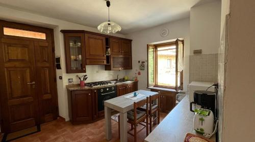 a kitchen with wooden cabinets and a table in it at La casina nel Borgo in Cetona