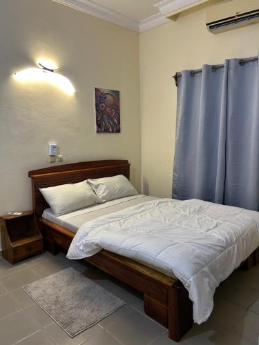 a bed in a bedroom with a blue curtain at Al appartement in Cotonou
