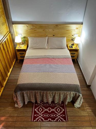 a bed in a small room with two tables and two lamps at Guazú Departamentos in Puerto Iguazú