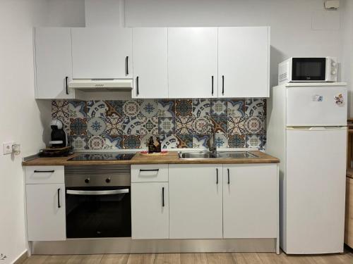 a kitchen with white cabinets and a sink and a refrigerator at Nuestro lugar feliz Apartamento Barbate - Patio ducha exterior in Barbate