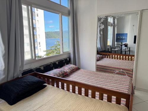 a bedroom with two beds and a large window at Conforto perto do Mar em São Vicente! in São Vicente