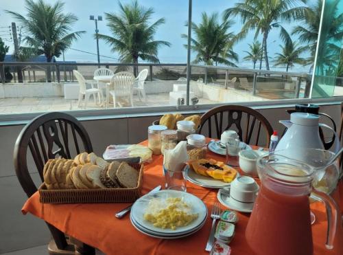 een tafel met ontbijtproducten op een balkon met uitzicht op het strand bij Ancora Peruibe Hotel in Peruíbe