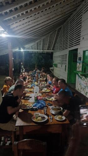 a group of people sitting at a long table eating food at Eco lodge finca magdalena in Altagracia