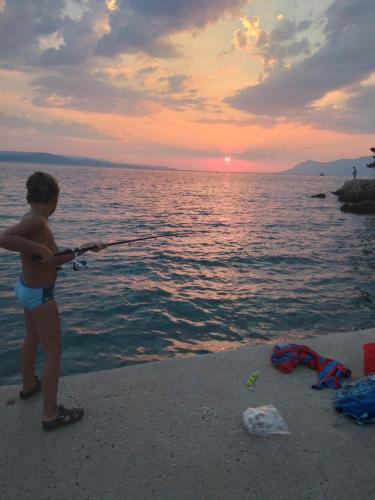 a young boy standing on the beach holding a fishing rod at Apartment Hortenzija in Baška Voda