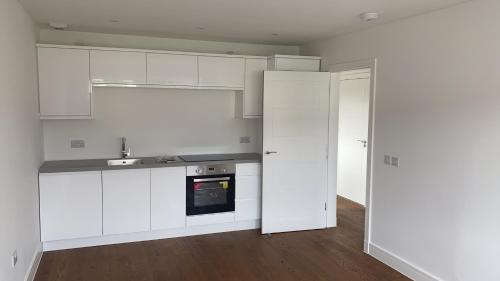 an empty kitchen with white cabinets and a sink at Cosy apartment near Edinburgh city centre in Edinburgh