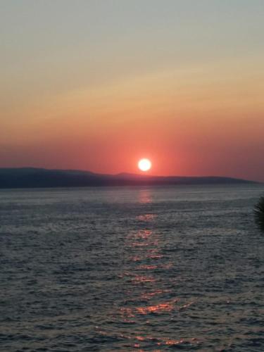 a sunset over the ocean with the sun in the sky at Apartment Hortenzija in Baška Voda