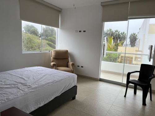 a bedroom with a bed and a chair and a window at Acogedora casa de playa para la familia y amigos in San Antonio