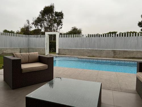 a patio with a chair and a pool with a fence at Acogedora casa de playa para la familia y amigos in San Antonio