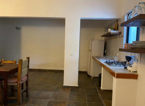 a kitchen with a counter and a table and a refrigerator at Costa Ayala casa para 18 personas a cuadra y media de la playa in Los Ayala