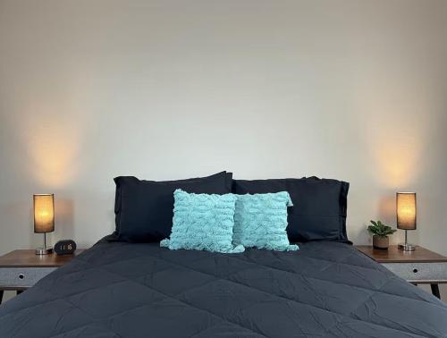 a bed with two blue pillows and two lamps at Cozy Home in Visalia