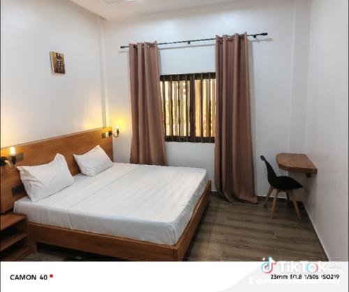 a bedroom with a bed and a desk and a window at Résidence Geordani in Cotonou