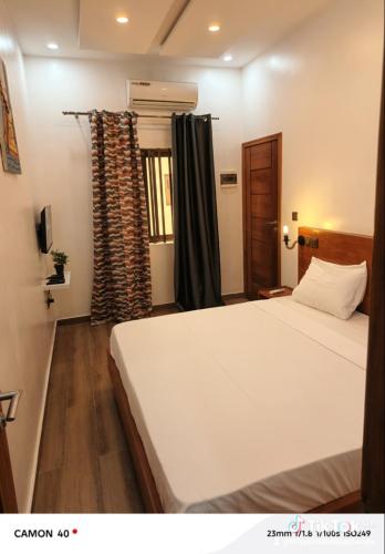 a bedroom with a large white bed and a window at Résidence Geordani in Cotonou