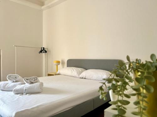 a bedroom with a bed with white sheets and a plant at New Residence Emilia in San Donato Milanese