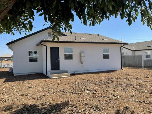 a white house with a black door at Ocean Breeze Harrison Ranch 2 in Visalia