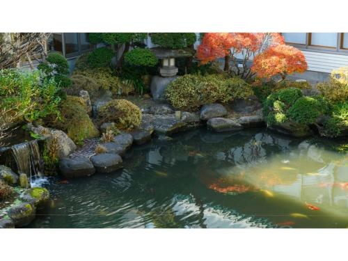 a koi pond in a garden with a fountain at Hotel Symphony - Vacation STAY 85392v in Sagae