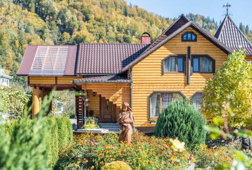 a wooden house with a statue in front of it at Хата Різьбяра in Beloberëzka