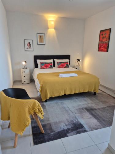 a bedroom with a bed with a yellow blanket and a chair at AQUAWAVES - Appartement T2 CARLA SUN - Saint-François in Saint-François