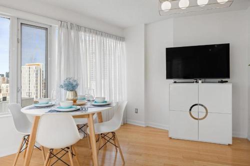 a white dining room with a table and a tv at High Rise 2BR Contemporary Condo w City Views next to Eaton Centre in Toronto