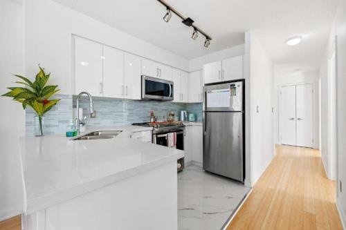 a kitchen with white cabinets and a stainless steel refrigerator at High Rise 2BR Contemporary Condo w City Views next to Eaton Centre in Toronto