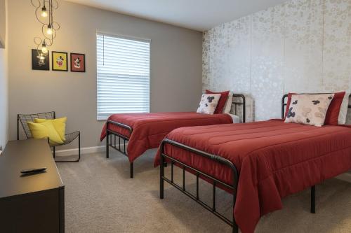 a bedroom with two beds with red sheets and a window at Storey lake 4BD/3BA BrandNew luxury pvt pool in Kissimmee