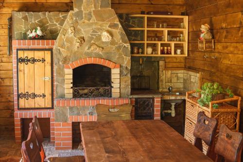 a kitchen with a stone fireplace and a wooden table at Хата Різьбяра in Beloberëzka
