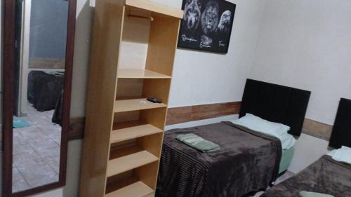a bedroom with a bed and a book shelf at Pousada Imperial in Itaboraí
