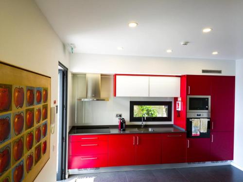 eine Küche mit roten Schränken und einer Spüle in der Unterkunft Casa das Andorinhas in Estreito da Calheta