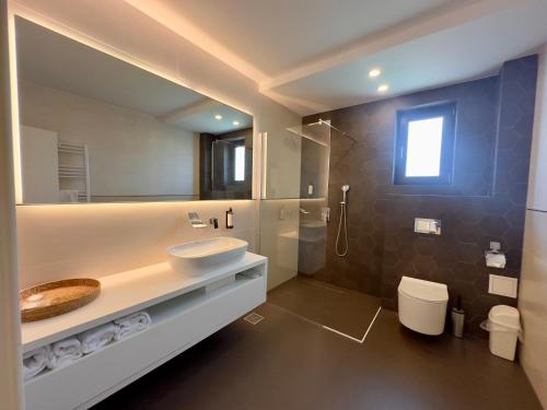 a bathroom with a sink and a toilet and a mirror at Mamaia Moments Villa, Mamaia Nord in Mamaia Nord