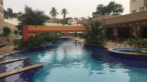 een groot zwembad in een hotel met palmbomen bij Apartamento dentro de um Resort 6 in Olímpia