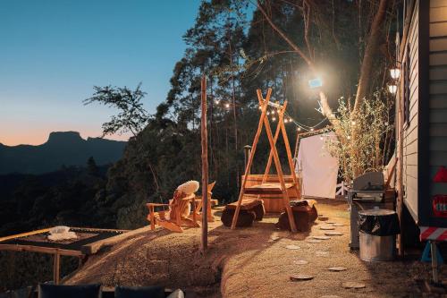 um pátio com uma mesa e cadeiras e uma montanha em Chalé europeu com vista infinita e cinema em C. do Jordão em Campos de Jordão