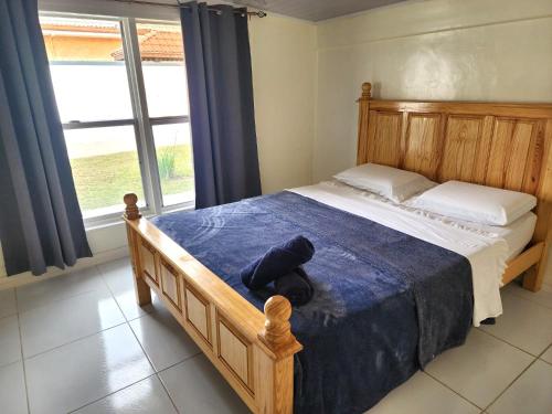 a bedroom with a wooden bed with a blue blanket at Ideal Executive Suites in Georgetown