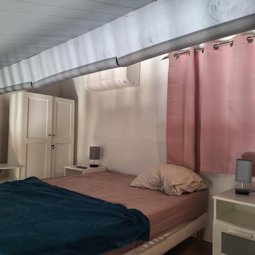 a bedroom with a bed with pink curtains at Mazet l'olivier 2 in Saint-Martin-de-Brômes