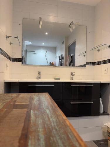a bathroom with a large mirror and a wooden table at Superbe appartement avec piscine et parking in Fréjus