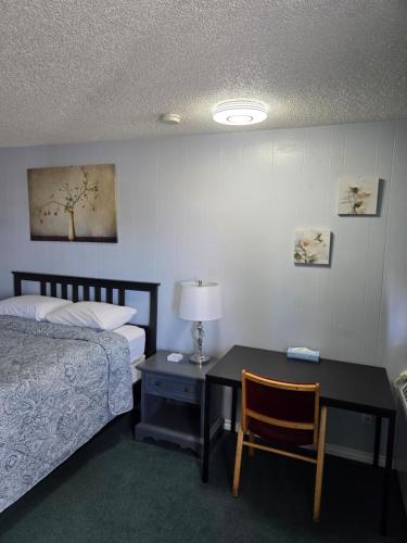a hotel room with a bed and a desk with a bed and a table with at Bio Vista Motel in Wainwright