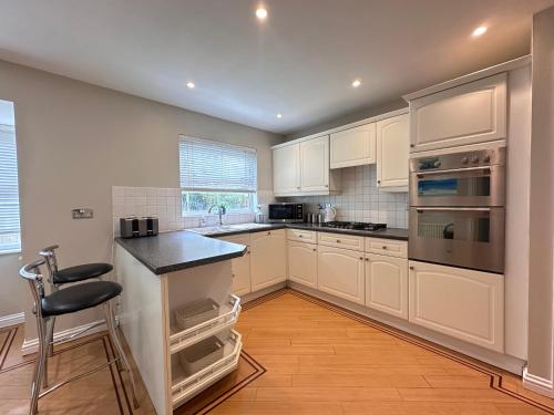 a kitchen with white cabinets and a black counter top at Spacious 4 Bed Home near Elizabeth Line, great for Contractors, Families, Groups & Insurance stays in Romford