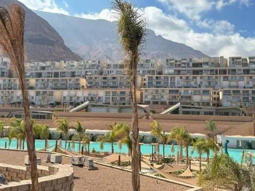 a resort with palm trees and a large building at شاليه للايجار في المونت جلاله العين السخنه 3 غرف مكيف بالكامل in Ain Sokhna