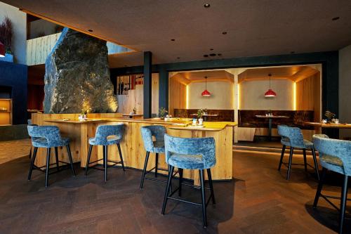a restaurant with a bar with blue stools at La Tambra - Hotel Lodge in Santa Cristina in Val Gardena